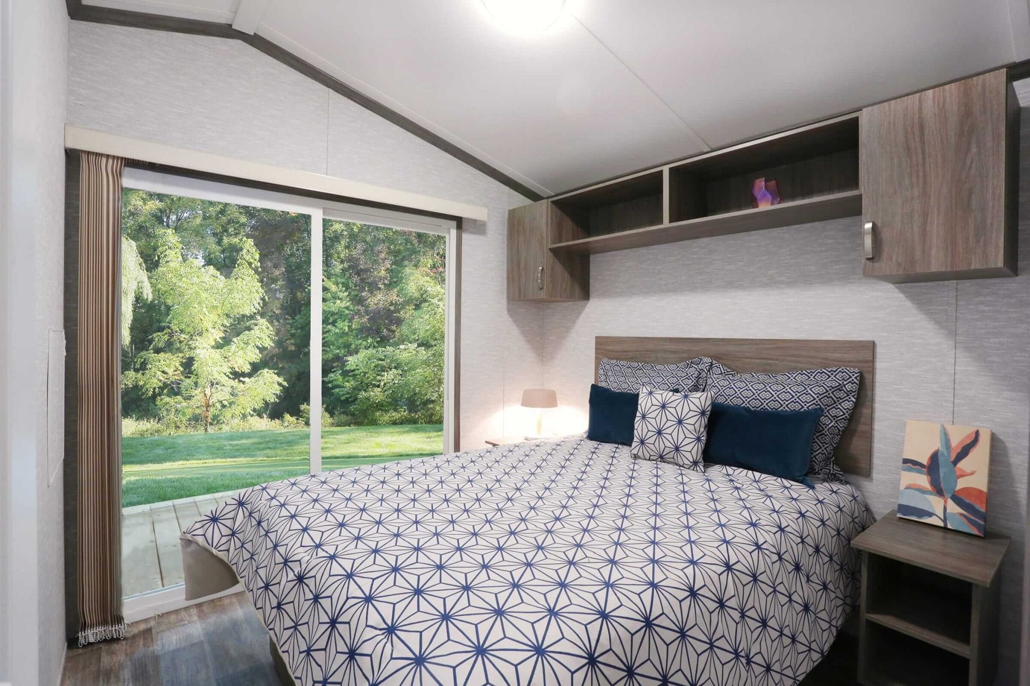 Bedroom featuring a bed, dresser, and a sliding glass door, showcasing the Frontier Series design.