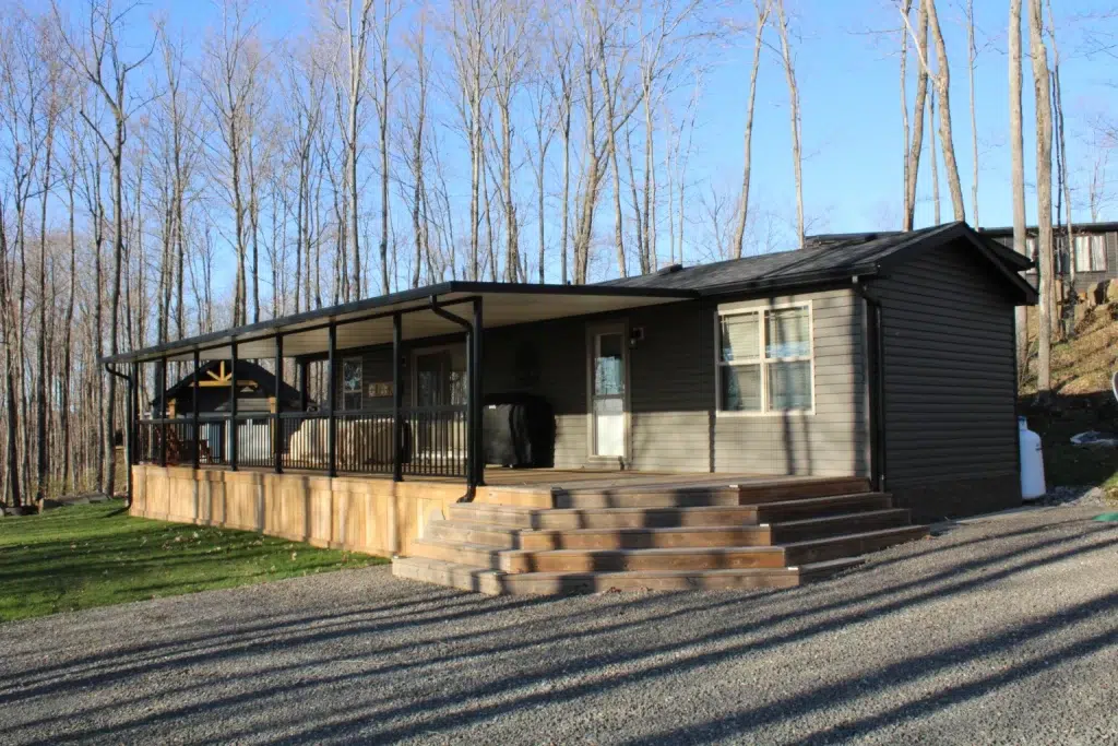 A cozy cabin featuring a covered porch and a spacious deck, perfect for outdoor relaxation and enjoyment.