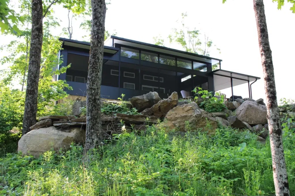 Modern house nestled among trees and rocks, showcasing a harmonious blend of nature and contemporary design.
