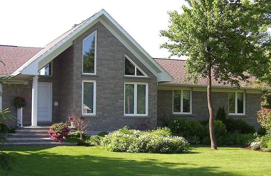 A charming house surrounded by a spacious lawn and trees, showcasing KV Windows & Doors.