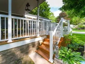 A beautiful deck with wooden stairs and white Aluminum Picket Railings, with a mix of pickets and glass panels.
