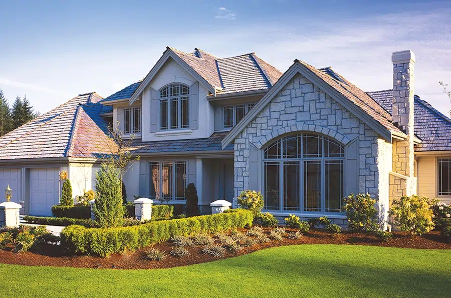 Large house with a spacious lawn and landscaped garden, showcasing Custom Windows & Doors.
