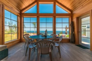 Sunroom featuring a table and chairs, showcasing a scenic ocean view, highlighting WeatherMaster™ Windows.
